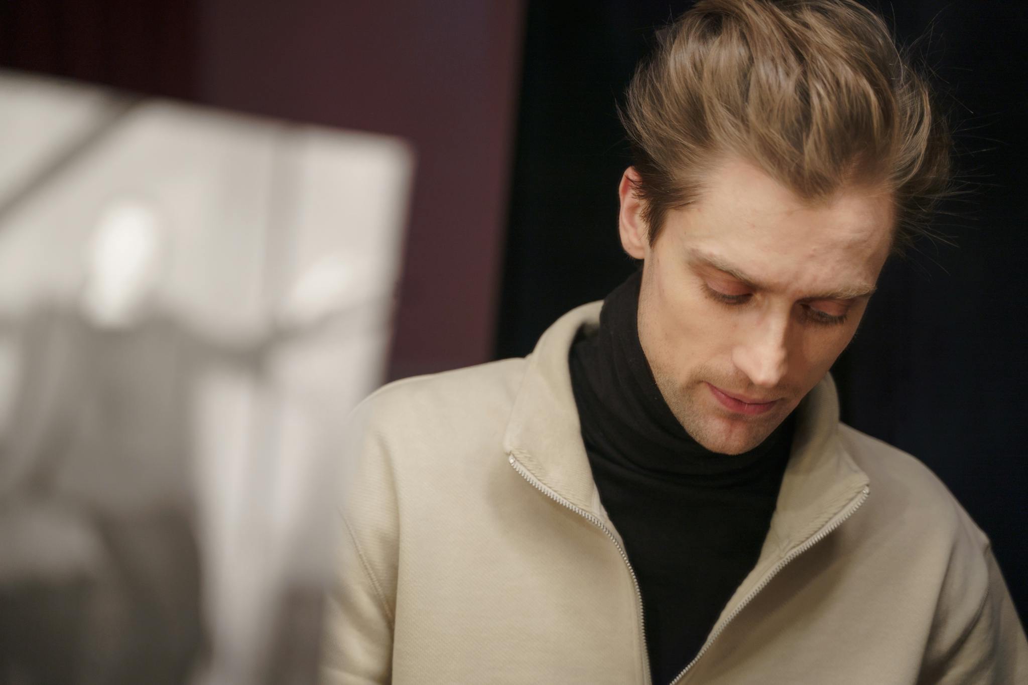 A thoughtful actor in a theater setting, deeply engaged in reviewing his script backstage.