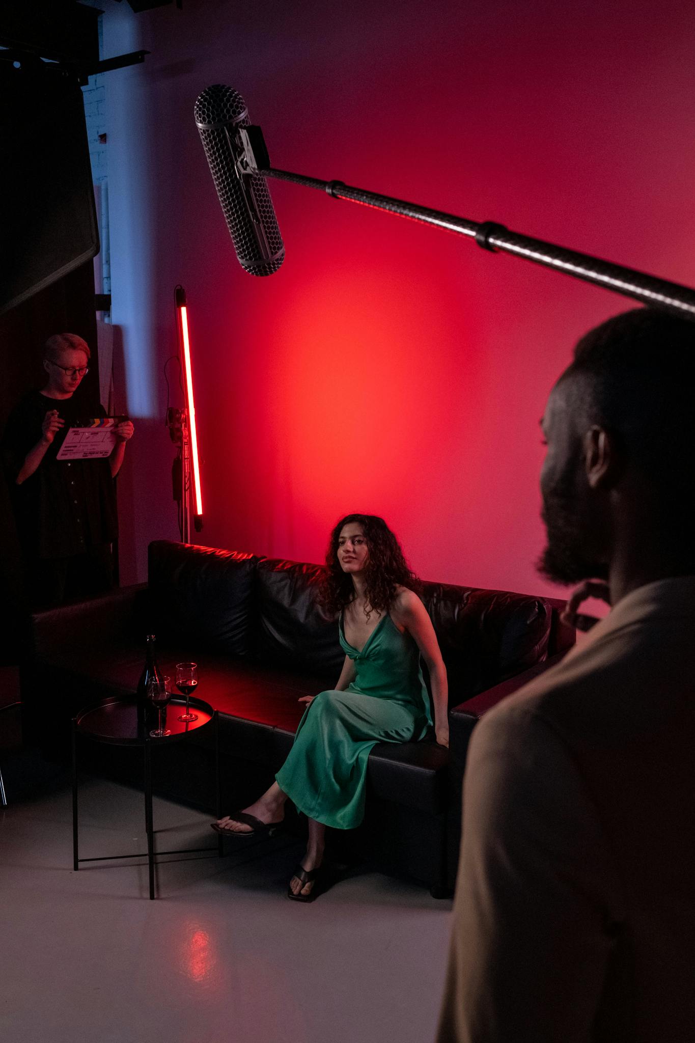 Inside a film studio with actors rehearsing on a red-lit set.